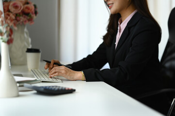 Cropped shot of female economist sitting at desk, working on investment and marketing projects.