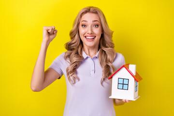 Fototapeta na wymiar Portrait of ecstatic overjoyed woman with wavy hairdo dressed purple t-shirt win new apartments isolated on yellow color background
