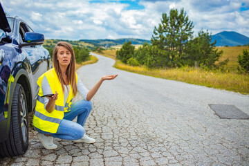 Young girl with damaged car waving with hand for assistance. Stop please. Young woman standing and hitchhiking in front of a open hood of her car in the city street.