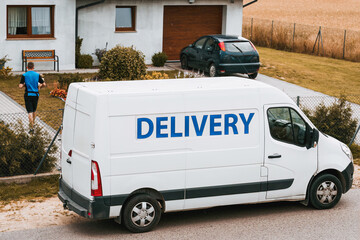 A white delivery van is parked on the roadside. Parcel logistics concept. Door-to-door overnight delivery company. © AlexGo