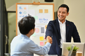 Millennial businessman shaking hands with partner closing deal or making agreement after successful negotiations.