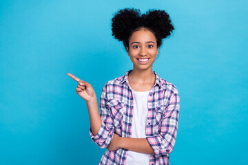 Photo of positive cheerful lady wear plaid shirt pointing finger empty space isolated blue color background