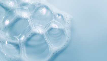 Foam border design on blue background. Liquid soap bubbles, Foam bubbles background. Soap foam popping bubble, white backdrop. Soap sud macro structure. Soap foam close-up. Clean, cleaning, washing. 