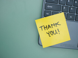 Top view of words thank you written on sticky note on laptop keyboard