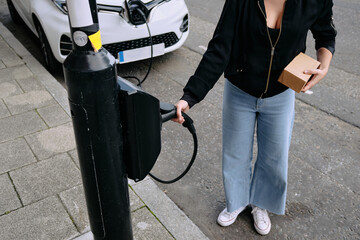 Woman Charging Electric Car at Charging Station