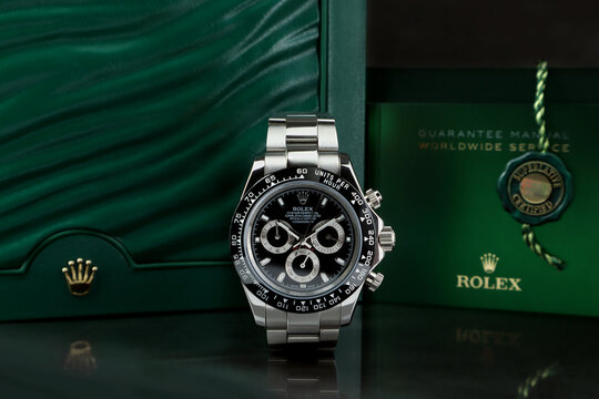 The Rolex vintage wristwatch ceramic bezel Cosmograph Daytona model display on mirror shelf table with background of Rolex green box crown logo , coin and manual and guarantee book in Rolex shop