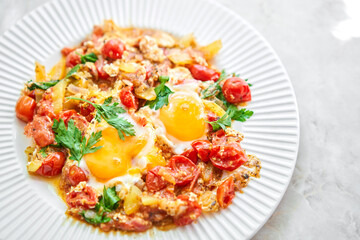 Shakshouka for breakfast. Homemade shakshuka, fried eggs, onion, bell pepper, tomatoes and parsley in a pan. Marble background. Top view. chakchouka