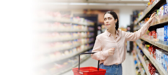 Web banner of shopping in supermarket. Portrait of young attractive caucasian woman takes food from...