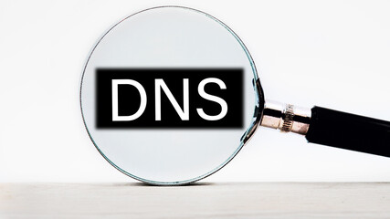 DNS -Domain Name Server lettering on through a magnifying glass on a light background