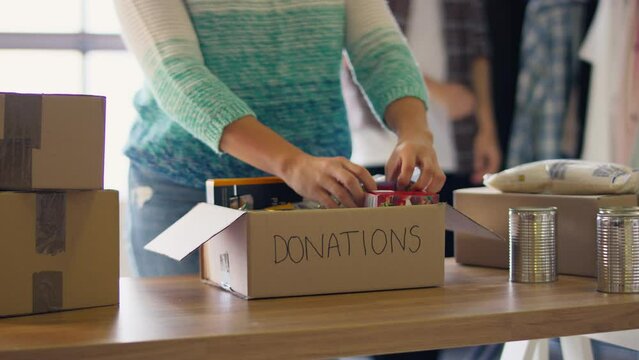 Close up of female charity worker at food bank sorting through donations - shot in slow motion