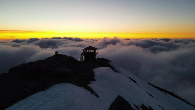 Flying above the clouds towards the sunset with a revealing view of the mountain summit of Mount Rainier volcano, beauty in nature