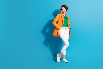 Fototapeta na wymiar Full body photo of young successful business lady wear orange blazer white pants it company team lead isolated on blue color background