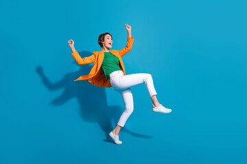 Fototapeta na wymiar Profile side full length photo of carefree crazy funky lady wear trendy orange clothes celebrate victory isolated on blue color background