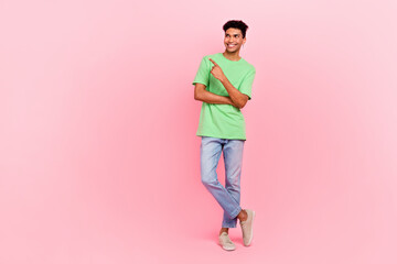 Full length photo of cheerful man with earrings dressed stylish t-shirt look directing empty space isolated on pink color background