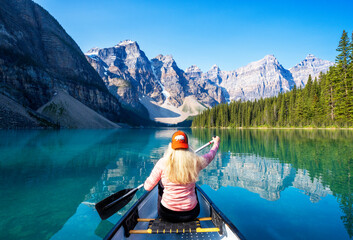 Woman enjoying early Morning Canoeing,.Moraine Lake during summer in .Banff National Park, Canadian Rockies, Alberta, Canada...Banff National Park, Alberta, Canada