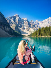 Woman taking a selfie in a Canoe,.Moraine Lake during summer in .Banff National Park, Canadian Rockies, Alberta, Canada...Banff National Park, Alberta, Canada