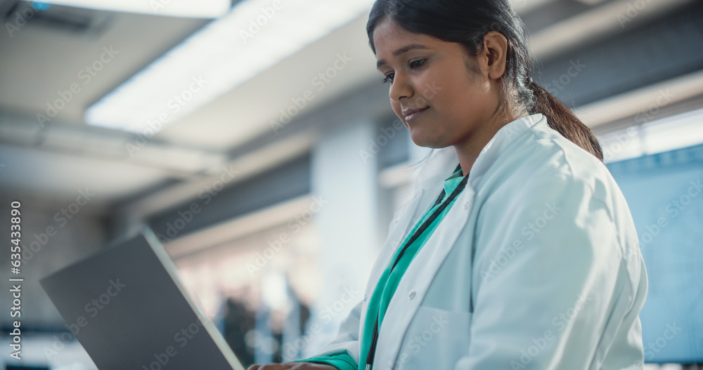 Aufkleber Young Indian Female Engineer Testing Futuristic Programmable Robot Animal in a Factory Development Workshop. Professional Researcher in a Lab Coat Developing AI Canine Prototype, Using Laptop Computer