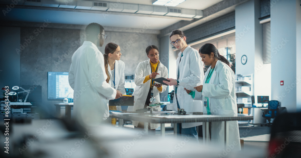 Poster Young Engineers Working in Company Facility Lab: Group of International Multiethnic Lab Specialists Gathering Around a Table to Discuss Blueprints and Components for a High Technology Robotic Project