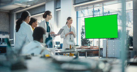 Group of Students Listening to Their Robotics Female Professor Who Uses Green Screen Monitor in a Laboratory. Team of Engineers Having Meeting and Discussing Manufacturing Ideas, Using Technology