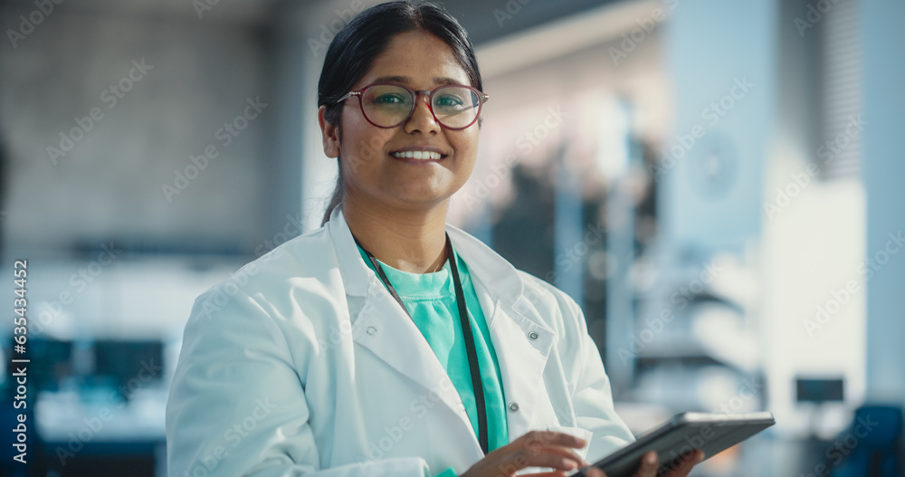 Poster portrait of indian young female scientist using digital tablet computer, looking at camera and smili
