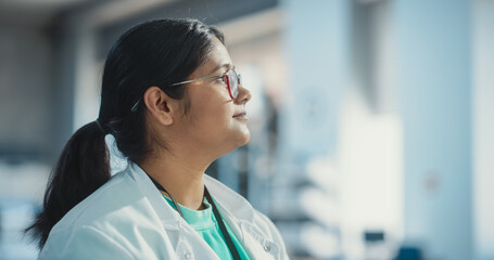 Profile Portrait Close Up of Young Indian Female Specialist Wearing Lab Coat and Glasses. Professional and Successful Woman Working as an Engineer, Science Student in University Laboratory Posing