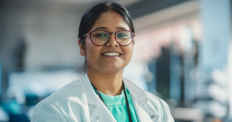 Portrait Close Up of Young Indian Female Specialist Wearing Lab Coat and Glasses Smiling....