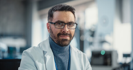 Portrait of Handsome Man Wearing Glasses and a Lab Coat Looking at the Camera. Senior Engineer...