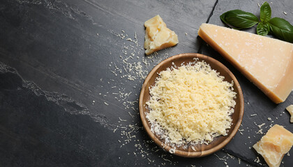 Whole and grated parmesan cheese on black table, flat lay. Space for text