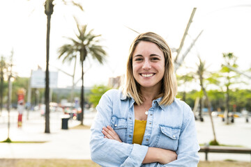 Portrait of beautiful happy young woman smiling and looking at camera with arms crossed in the...