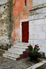 Fototapeta na wymiar Porta di una chiesa con scalette e vaso di fiori