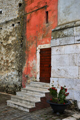 Fototapeta na wymiar Porta di una chiesa con scalette e vaso di fiori