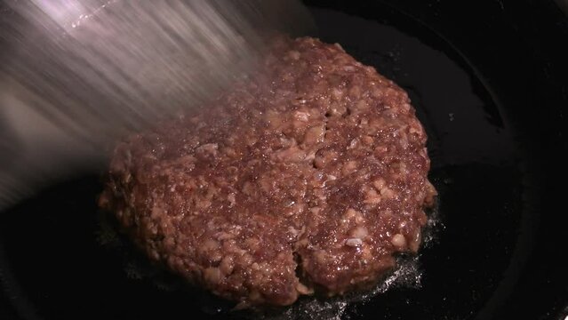 Meat cutlet is fried in a pan. Cooking for a meal in kitchen.