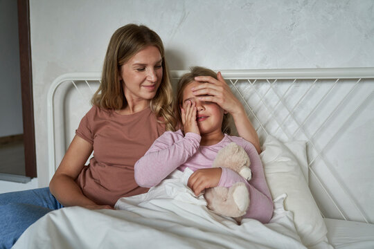 Mother talking to her ill girl child lying in bed