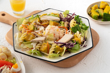 Fresh avocado lettuce salad bowl with chicken meat in a plate on white table background.
