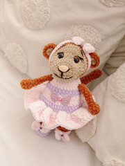 Knitted toy monkey on white wall background. Natural. Toy for girl. Toy monkey in dress