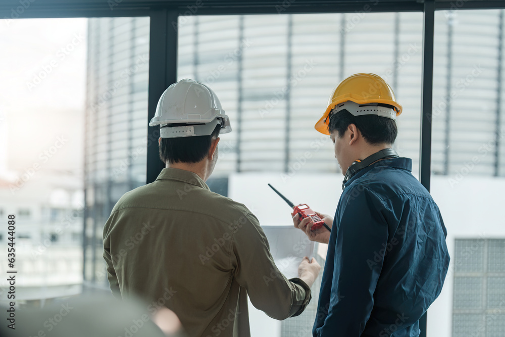 Poster two engineer man checking work with walkie-talkie for communication in the construction site