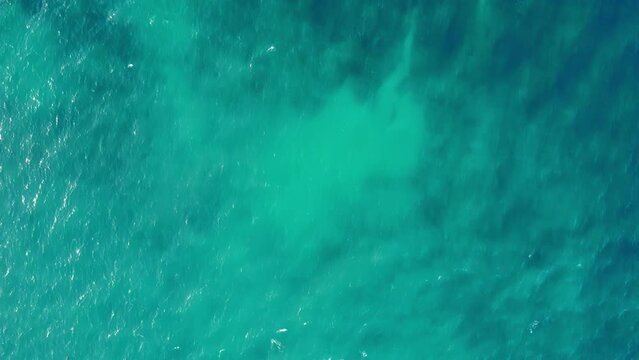 Overhead view of shallow endless turquoise sea water. Infinite green and blue ocean waters covered with small calm waves