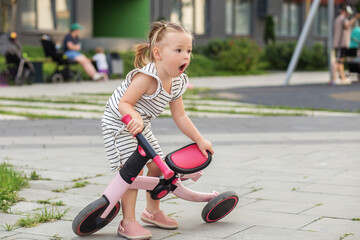 Little child falling off tricycle. Learning to ride bike concept. Summer time.