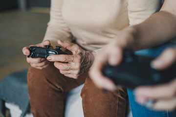 Close-up senior woman hands using gamepad joysticks, virtual player, enjoying family leisure time, funny playtime.