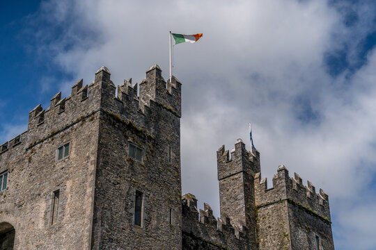 Crenellated towers on Bunratty castle donjon with green, white, orange irish flag flying proudly
