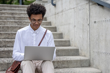 Curly-haired young digital nomad working outside and looking happy