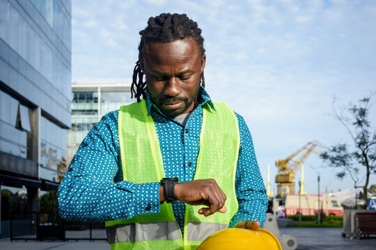 black man chief construction engineer at end of day finishing work looking at time on his watch