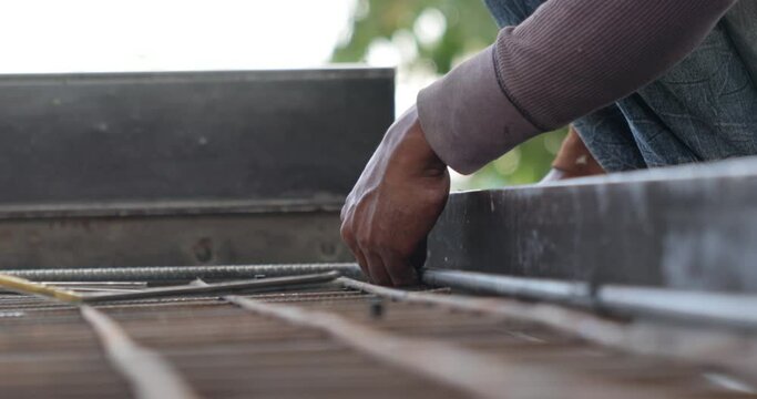 Reinforced concrete structures. Construction worker uses pilers tools and steel tying wire to fasten steel rods of concrete wall at Heavy Industry Manufacturing Factory. Prefabricated concrete walls