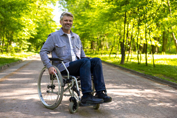 Gray haired disable man in wheelchair spending free time in park.