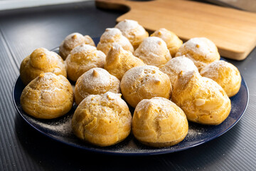 Freshly baked profiteroles on a plate. food concept. dessert. bakery.