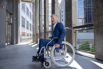 Fototapeta na wymiar Gray haired disabled man wearing official style suit in wheelchair city background.