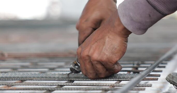 Reinforced concrete structures. Construction worker uses pilers tools and steel tying wire to fasten steel rods of concrete wall at Heavy Industry Manufacturing Factory. Prefabricated concrete walls