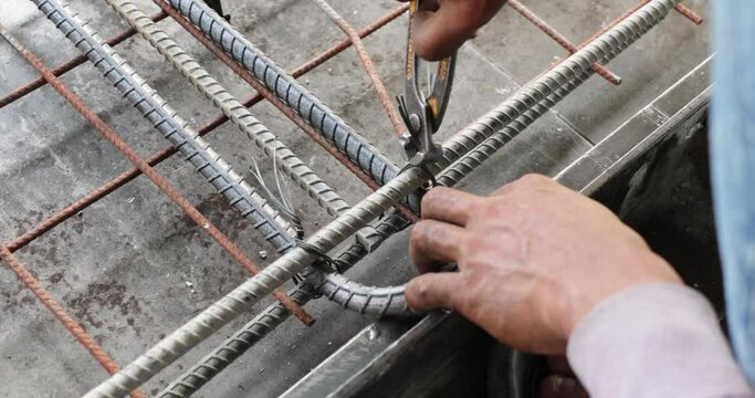 Reinforced concrete structures. Construction worker uses pilers tools and steel tying wire to fasten steel rods of concrete wall at Heavy Industry Manufacturing Factory. Prefabricated concrete walls