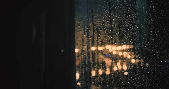 Close-up of woman looking to window during torrential rainstorm with lightning, close-up