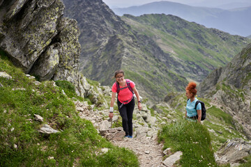 Naklejka na ściany i meble Women hiking on a trail in the rocky mountains